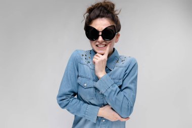 Gri izole büyük güneş gözlüğü takıyor topuz saç modeli ile mutlu esmer beyaz kız