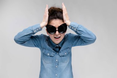 Gri izole büyük güneş gözlüğü takıyor topuz saç modeli ile mutlu esmer beyaz kız