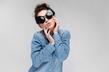 Gri izole büyük güneş gözlüğü takıyor topuz saç modeli ile mutlu esmer beyaz kız