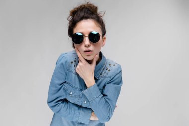 Gri izole yuvarlak güneş gözlüğü takıyor topuz saç modeli ile genç esmer beyaz kız