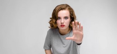 Dur jest gri arka plan üzerinde gösterilen güzel kızıl saçlı mutlu genç kadın portresi