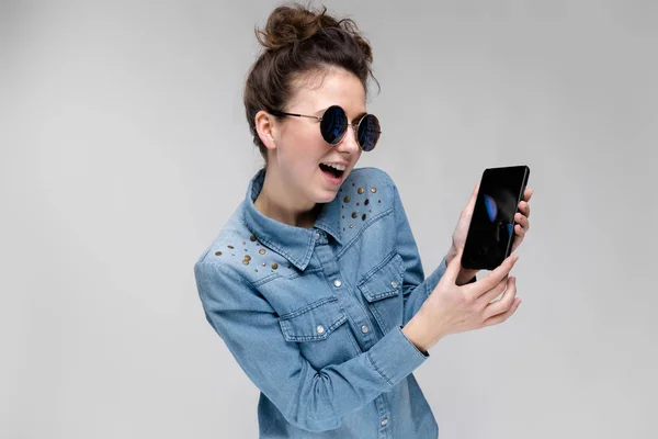 Junge Brünette Kaukasische Mädchen Mit Dutt Frisur Sonnenbrille Zeigt Smartphone — Stockfoto