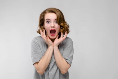 Gri arka plan üzerinde yapması güzel kızıl saçlı mutlu genç kadın portresi