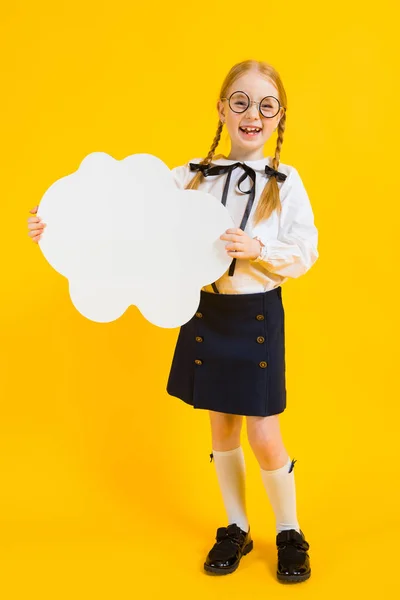 Girl with red pigtails on a yellow background. A charming girl in round transparent glasses is holding a white cloud in her hands.