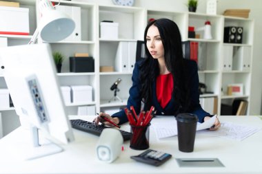 Bilgisayar ve ofis belgeleri ile masada çalışan güzel bir genç kız.