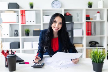 Hesap makinesi ve Office belgeleri ile masada çalışan güzel bir genç kız