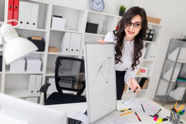 Güzel bir genç kız bir Ofis Masası standları ve manyetik bir işaretleyici manyetik tahtaya çizer.