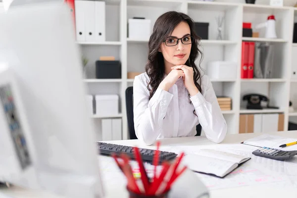 Menina bonita está sentada à mesa no escritório . — Fotografia de Stock