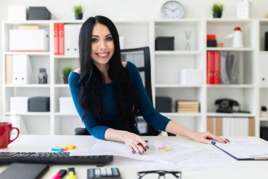 Onun elinde kalem tutan ve belgeleri doldurma parlak ofisinde çalışan güzel bir genç kız.