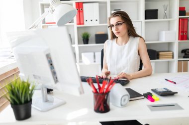 Güzel genç kız masa ofis ve yazarak metin klavyede oturur.