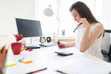 Ofiste genç bir kız pembe bir marker, gözlük ve çalışma belgeleriyle tutuyor.