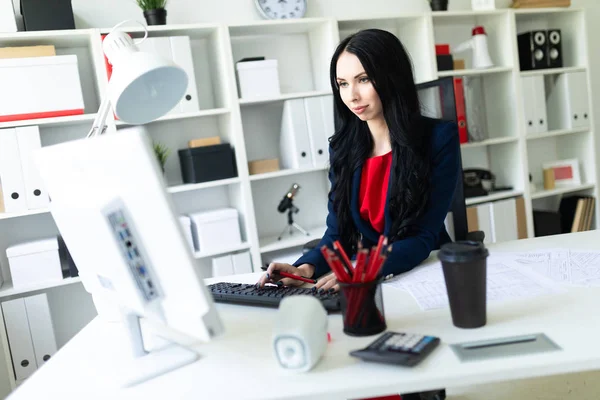 Красивая молодая девушка, работающая с компьютером и документами в офисе за столом . — стоковое фото