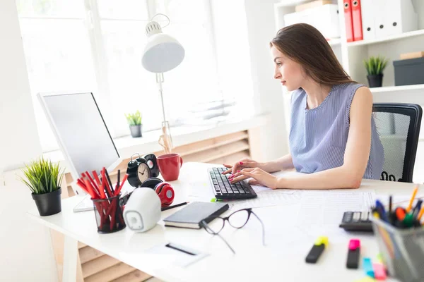 Hermosa joven en la oficina se sienta en la mesa y las impresiones en el teclado . — Foto de Stock