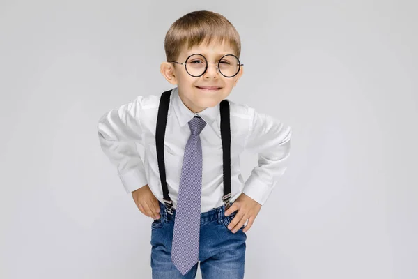 リスニングのサインを作る眼鏡と灰色の背景の上に立って小さな男の子の肖像画 — ストック写真
