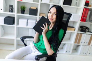 Genç bir kız ofis masada oturur ve bir defter elinde tutan.