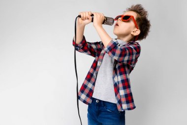 Gri arka plan üzerinde mikrofon şarkı duran ile büyüleyici mutlu çocuk