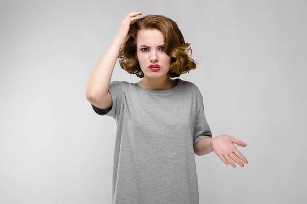 Encantadora joven con una camiseta gris sobre un fondo gris. Una chica sostiene su mano detrás de su cabeza — Foto de Stock