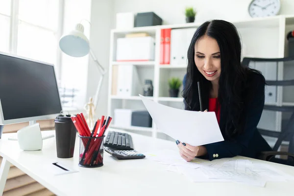 Schönes junges Mädchen arbeitet im Büro am Tisch mit Dokumenten und hält einen Bleistift in der Hand. — Stockfoto