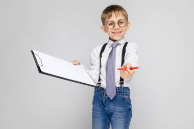 Kalem ve belgeleri holding gri arka plan üzerinde duran küçük çocuk portresi