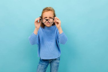 Mavi arka planda gözlüklerle poz veren küçük akıllı kız 