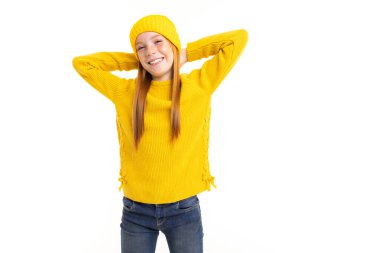 Sarı kazaklı ve şapkalı tatlı genç kız beyaz arka planda poz veriyor.  