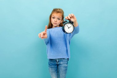 Mavi arka planda saat alarmı ile poz veren küçük kız 