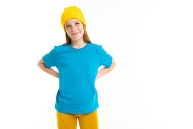 Beyaz arka planda poz veren sarı şapkalı tatlı genç kız. 