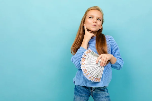 cute little girl with money posing against blue background