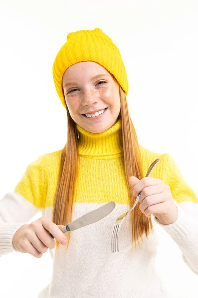 可愛いですティーン女の子でイエロー帽子ポーズとともにフォークとナイフで白い背景 — ストック写真
