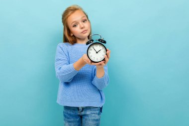 Mavi arka planda saat alarmı ile poz veren küçük kız 