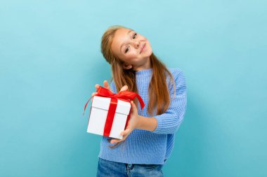 Mavi arka planda hediyeyle poz veren küçük kız 