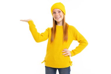 Sarı kazaklı ve şapkalı tatlı genç kız beyaz arka planda poz veriyor.  