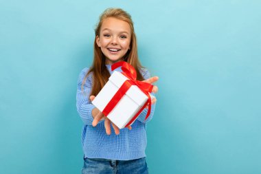 Mavi arka planda hediyeyle poz veren küçük kız 