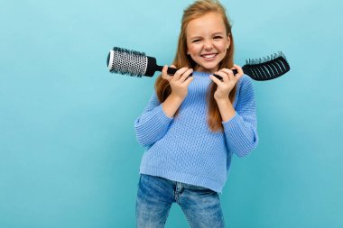 little girl posing with two hairbrushes against blue background 