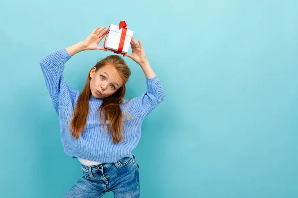 little girl posing with gift against blue background