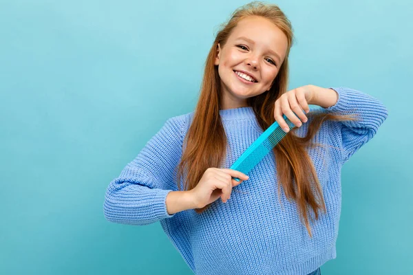 Mavi Arka Planda Saç Fırçasıyla Poz Veren Küçük Kız — Stok fotoğraf