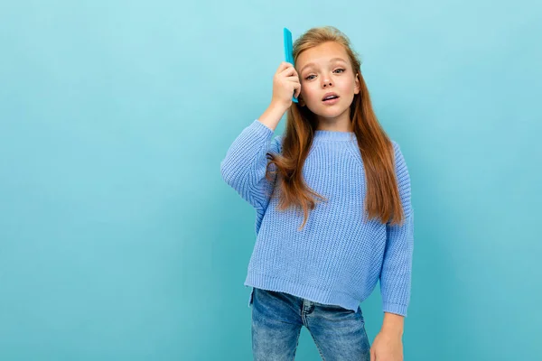 青い背景にヘアブラシでポーズをとる女の子 — ストック写真