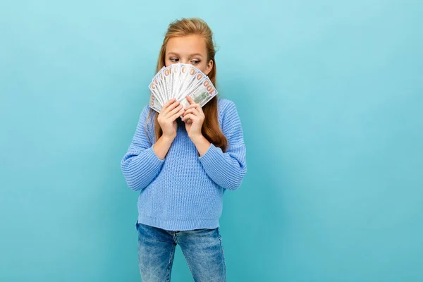 cute little girl with money posing against blue background