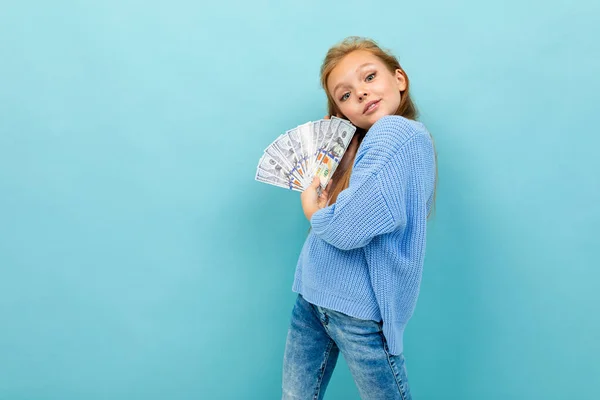 cute little girl with money posing against blue background