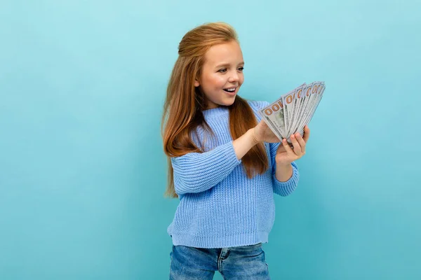 cute little girl with money posing against blue background