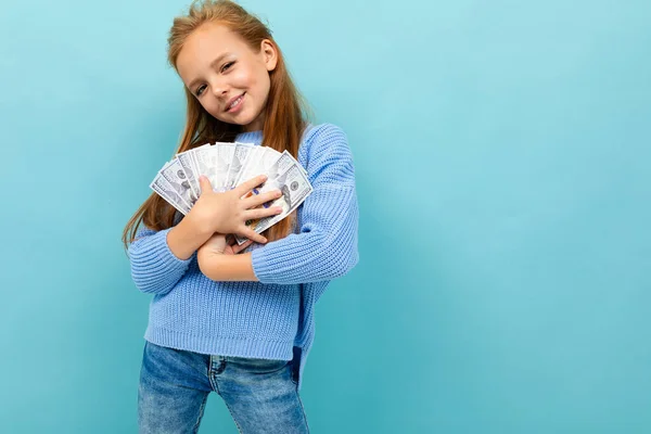 cute little girl with money posing against blue background