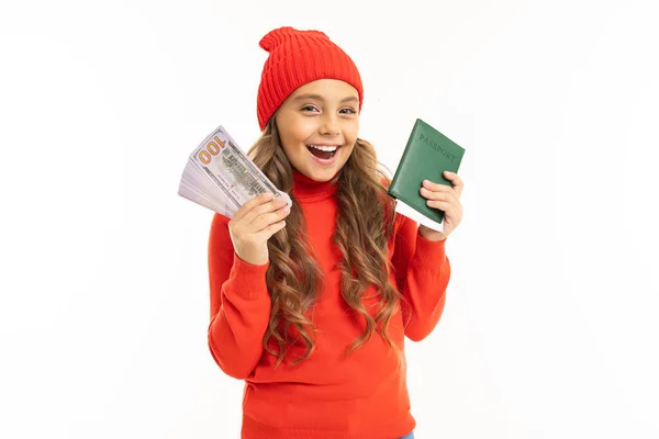 穿着红色毛衣 头戴红色帽子 头戴护照 身披白色背景钞票的可爱小女孩 — 图库照片