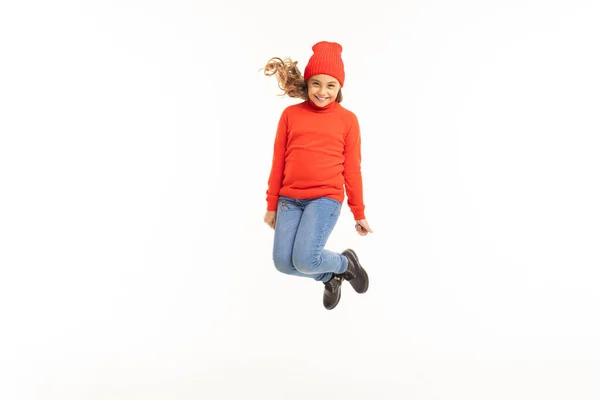 Bonito Menina Vermelho Suéter Chapéu Saltando Contra Branco Fundo — Fotografia de Stock