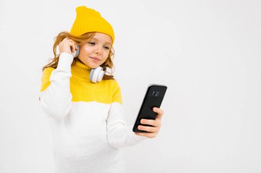 Stüdyoda kulaklık ve cep telefonuyla poz veren hoş bir kız. 