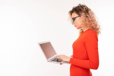young woman in red dress posing with laptop against white background  