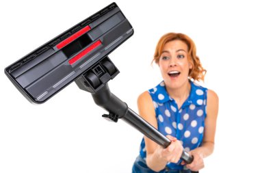 Genç kızıl saçlı kadın elektrik süpürgesi beyaz arka planda poz veriyor.  