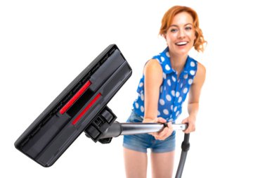 Genç kızıl saçlı kadın elektrik süpürgesi beyaz arka planda poz veriyor.  