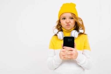 Stüdyoda kulaklık ve cep telefonuyla poz veren hoş bir kız. 