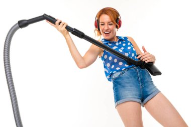 Genç kızıl saçlı kadın elektrik süpürgesi beyaz arka planda poz veriyor.  