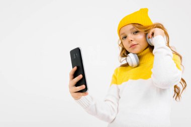 Stüdyoda kulaklık ve cep telefonuyla poz veren hoş bir kız. 